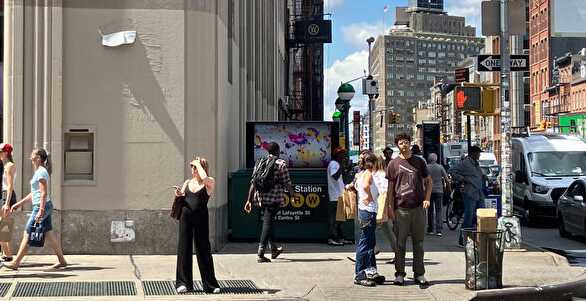 A group of people standing on a sidewalk

Description automatically generated