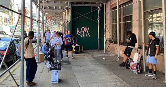 A group of people walking on a sidewalk

Description automatically generated